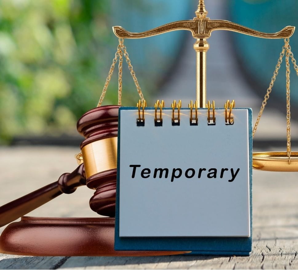 temporary legal directive A sign labeled "temporary" placed in front of a judge's gavel and scales of justice