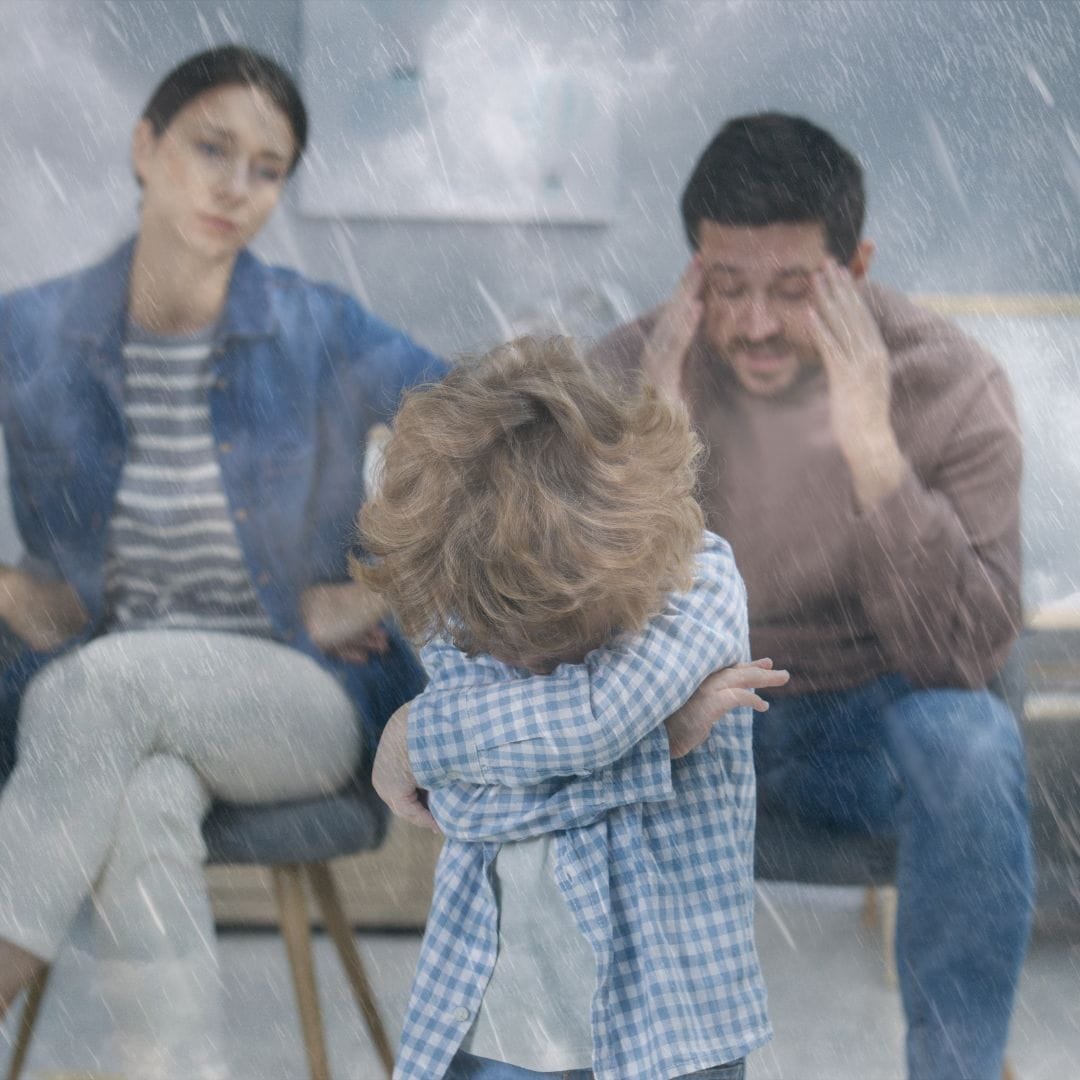 Parents arguing in front of their small boy who is hiding his face. Rainfall.