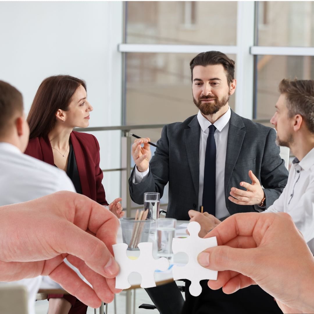 Business meeting with hands putting together puzzle pieces superimposed on it. Collaborative divorce meeting.