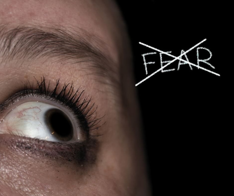 Close up of eyeball looking up at the word "Fear" with an x in it.