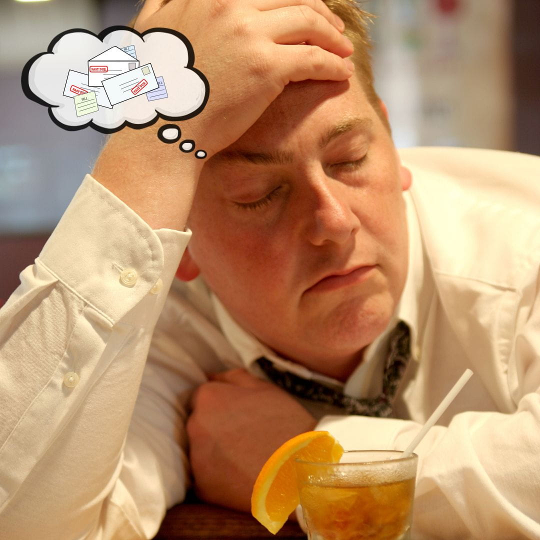Upset businessman with financial anxiety sitting at a bar with a drink and a thought bubble of bills hovers over his head.
