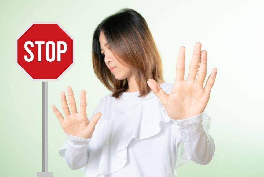 Woman gesturing "no" and a stop sign beside her, symbolizing boundaries